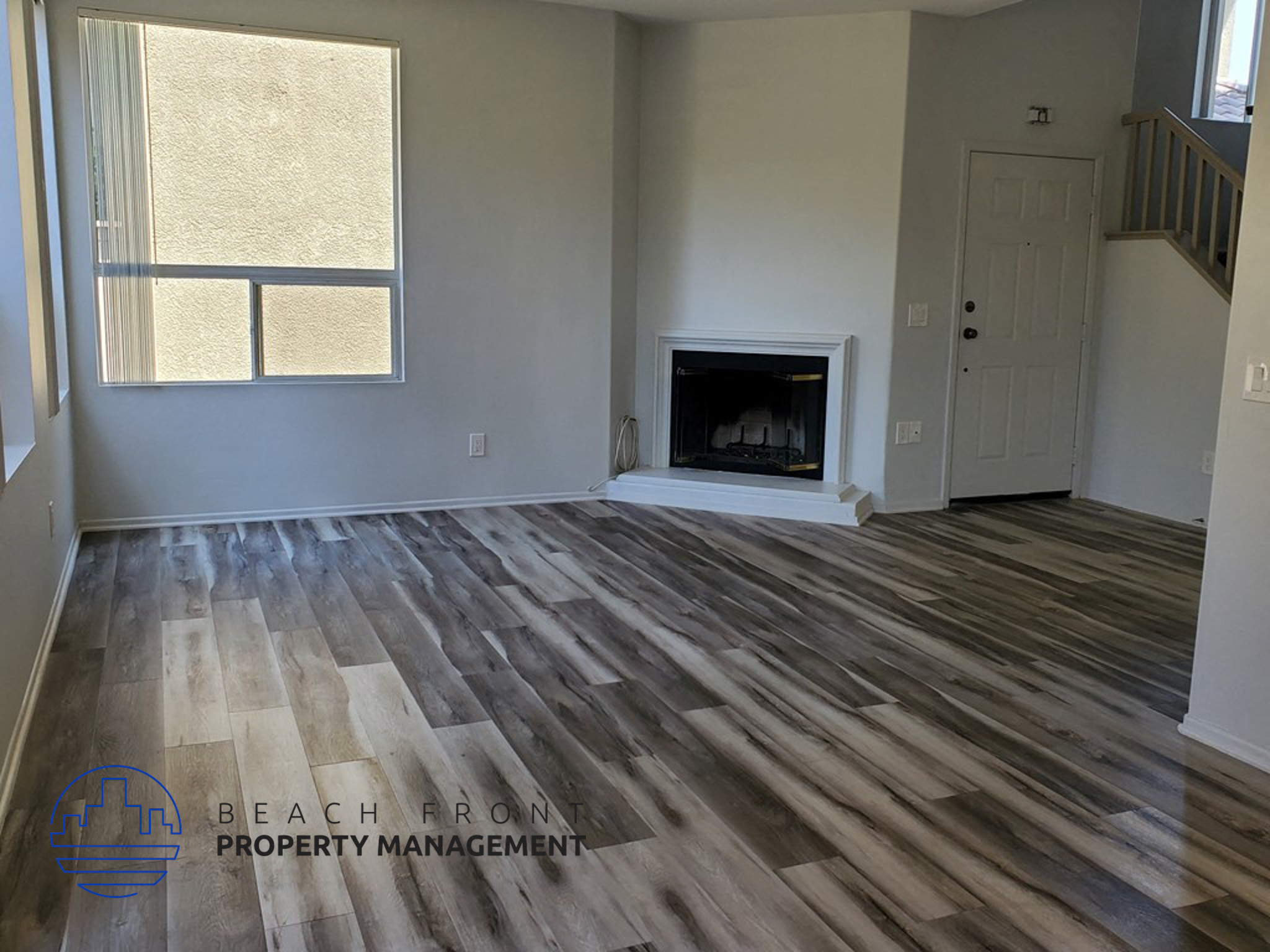 A living room with a fireplace and wooden floors.